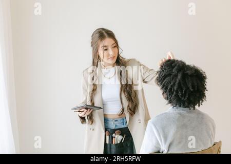 latina-Frau macht Make-up für afroamerikanische Klienten Stockfoto