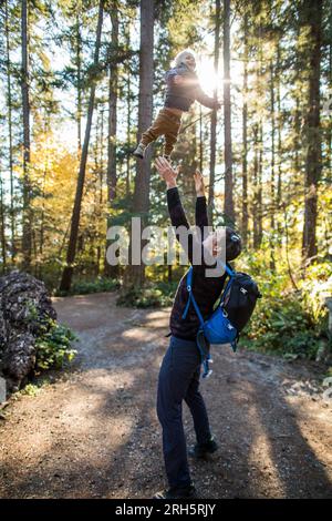 Vater hebt die Arme, um seinen Sohn zu fangen, der mitten in der Luft fliegt. Stockfoto