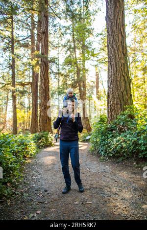 Vater balanciert seinen kleinen Sohn beim Wandern auf den Schultern Stockfoto