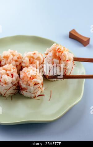 Ein Mann hält japanische Sushi-Brötchen mit Stäbchen in der Hand Stockfoto