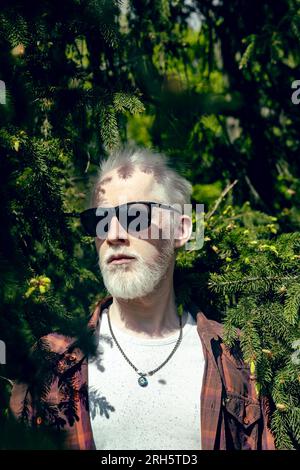 Albino-Mann in Sonnenbrille Nahaufnahme in Kiefern Stockfoto
