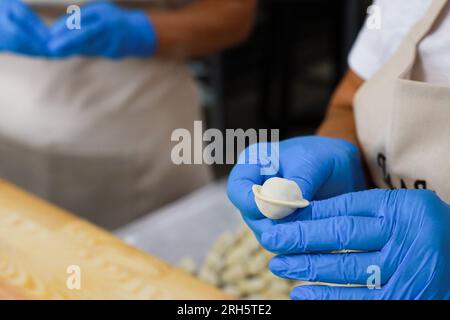 Eine Frau in Handschuhen vervollständigt die Form eines Knödels Stockfoto