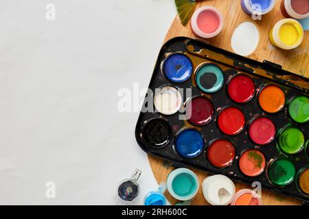 Flachlagerung von bunten Farben, Malerpalette und Pinseln auf weißem Hintergrund, Kunst, Malen und Hobbykonzept, Draufsicht, Kopierbereich. Stockfoto