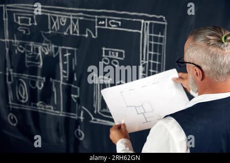 Senior Styling Mann, professioneller Architekt, der Skizzen, Architekturzeichnungen ansieht, neue Bauprojekte erstellt Stockfoto