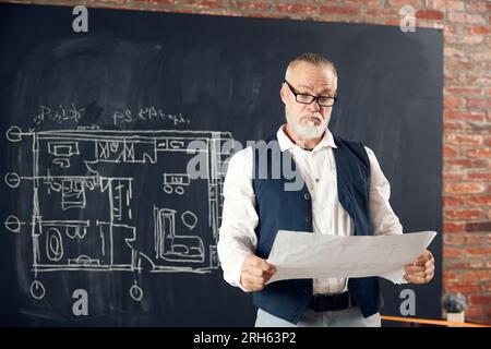 Senior Styling Mann, professioneller Architekt, der Skizzen, Architekturzeichnungen ansieht, neue Bauprojekte erstellt Stockfoto
