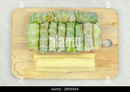 Verschiedene hausgemachte Halbfertigprodukte auf Holzbrettern. Gefrorene Kohlbrötchen und Pfannkuchenbrötchen. Zubereitungen aus hausgemachter Nahrung. Stockfoto