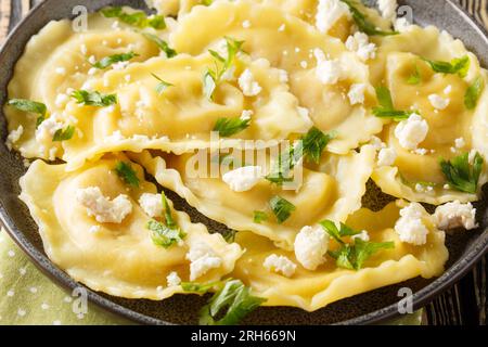 Hausgemachte Pasta Mezzaluna gefüllt mit Ziegenkäse und Kräutern, Nahaufnahme auf einem Teller auf dem Tisch. Horizontal Stockfoto