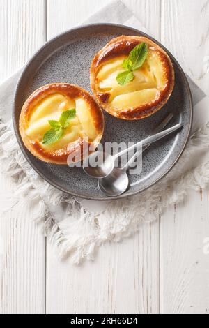 Klassische Backapfeltörtchen mit Pudding und Minze auf einem Teller auf dem Tisch. Vertikale Draufsicht von oben Stockfoto