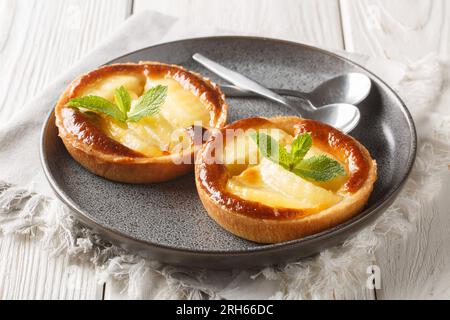 Festliche, frische Apfeltörtchen mit Vanillesauce und Minze-Nahaufnahme auf einem Teller auf dem Tisch. Horizontal Stockfoto