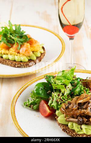 Zwei offene Sandwiches mit Pilzen und gesalzenem Lachs mit Sekt. Lebensmittelhintergrund. Stockfoto