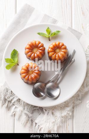 Regionale französische Küche Canele de Bordeaux aus nächster Nähe auf einem Teller auf dem Tisch. Vertikale Draufsicht von oben Stockfoto