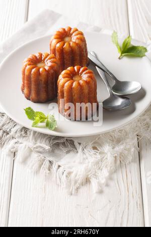 Regionale französische Küche Canele de Bordeaux aus nächster Nähe auf einem Teller auf dem Tisch. Vertikal Stockfoto