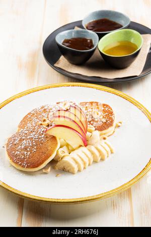 Βreakfast-Konzept. Pfannkuchen mit Obst und Sirup auf Holzhintergrund. Stockfoto