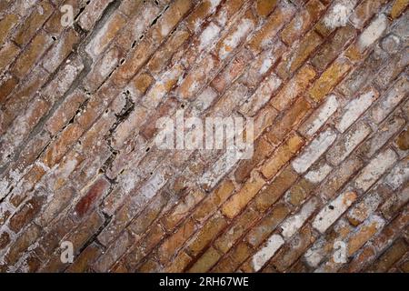 Textur einer antiken Wand aus Ziegeln in warmen Tönen und mit diagonaler Komposition. Stockfoto