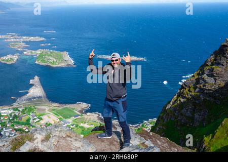 Entspannte, glückliche Wanderer genießen die atemberaubende Aussicht auf den Reinebringen-Gipfeln der Lofoten-Inseln, Fjorde, Norwegen Stockfoto