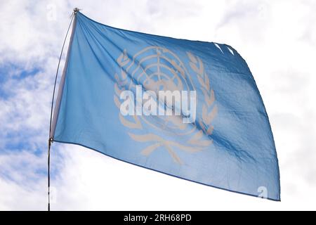 Hintergrundbeleuchtete UN-Flagge, die im Wind winkt. Offizielles Emblem der Vereinten Nationen. Konzept für den Weltfrieden Stockfoto