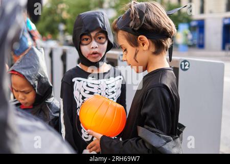 Vielfältige Gruppe von Kindern, die Halloween-Trick oder -Leckerbissen in den Straßen der Stadt genießen Stockfoto