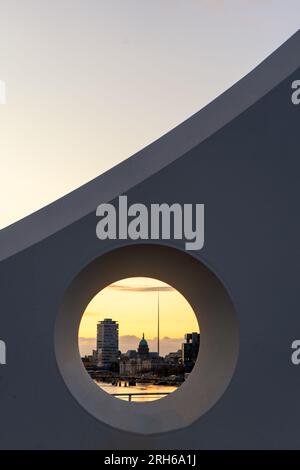 Fesselnder Blick bei Sonnenuntergang auf Dublins Skyline, eingerahmt vom eleganten Kreis der berühmten Samuel Beckett Bridge, die moderne Architektur mit natürlicher Umgebung verbindet Stockfoto