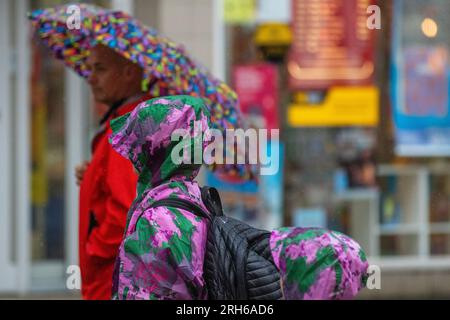 Southport, Merseyside. Wetter in Großbritannien. 14. August 2023; Wetter in Großbritannien. Um 19C Uhr regnet es warm, während die Käufer in Southport nass werden. Ausbrüche von Regenschauern in Nordengland und Wales heute Nachmittag, heftig und donnernd an einigen Stellen. Schwankende Wolken, sonnige Zauber und verstreute Schauer im Nordwesten. Kredit; MediaWorldImages/AlamyLiveNews Stockfoto