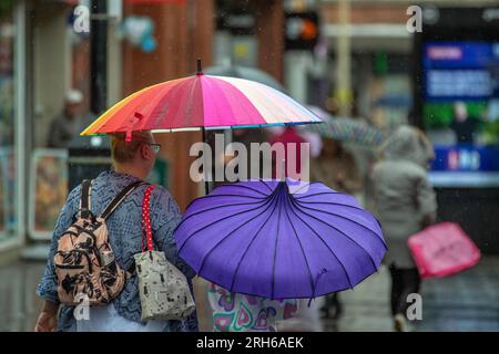 Southport, Merseyside. Wetter in Großbritannien. 14. August 2023; Wetter in Großbritannien. Um 19C Uhr regnet es warm, während die Käufer in Southport nass werden. Ausbrüche von Regenschauern in Nordengland und Wales heute Nachmittag, heftig und donnernd an einigen Stellen. Schwankende Wolken, sonnige Zauber und verstreute Schauer im Nordwesten. Kredit; MediaWorldImages/AlamyLiveNews Stockfoto