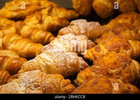 Leckere Croissants im Showcase. Bäckerei in goldener Farbe. Frisch gebackene französische Kuchen. - Das Gebäck. Köstliches Frühstück. Morgenbraten im Café. Stockfoto