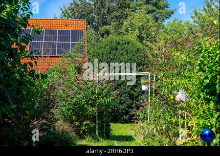 Dach eines Wohngebäudes mit Photovoltaik-System in einer Nachbarschaft mit Gärten in Berlin. Stockfoto