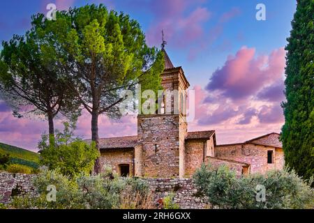 Foligno, Umbrien, Italien. Santa Croce Abbey (1070) in Sassovivo bei Sonnenuntergang mit rosa Wolken, umgeben von grüner mediterraner Natur. Stockfoto