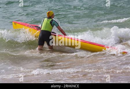 Frau, die im August Surfski-Ski im Meer vorbereitete, um Surfski-Ski am Branksome Chine Beach, Poole, Dorset, Großbritannien, zu fahren Stockfoto