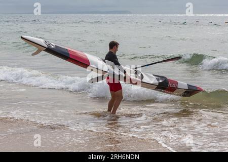 Ein Mann, der im August Surfski-Ski im Meer vorbereitete, um Surfski-Ski am Branksome Chine Beach, Poole, Dorset, Großbritannien, zu fahren Stockfoto