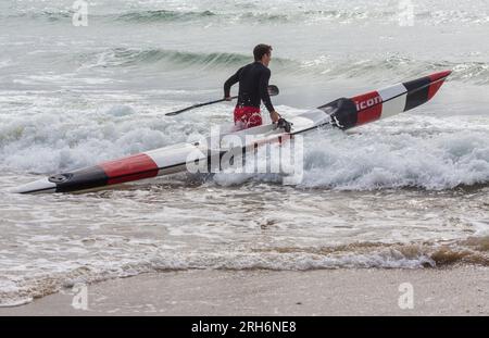 Ein Mann, der im August Surfski-Ski im Meer vorbereitete, um Surfski-Ski am Branksome Chine Beach, Poole, Dorset, Großbritannien, zu fahren Stockfoto