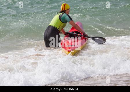 Frau, die im August Surfski-Ski im Meer vorbereitete, um Surfski-Ski am Branksome Chine Beach, Poole, Dorset, Großbritannien, zu fahren Stockfoto