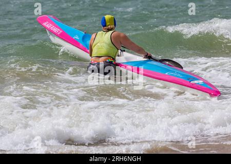 Frau, die im August Surfski-Ski im Meer vorbereitete, um Surfski-Ski am Branksome Chine Beach, Poole, Dorset, Großbritannien, zu fahren Stockfoto