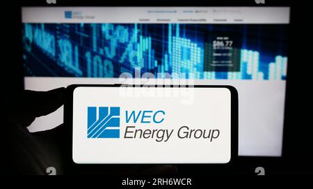 Person, die ein Mobiltelefon mit dem Logo des US-Versorgungsunternehmens WEC Energy Group Inc. Auf dem Bildschirm vor der Unternehmenswebseite hält. Konzentrieren Sie sich auf das Display des Telefons. Stockfoto