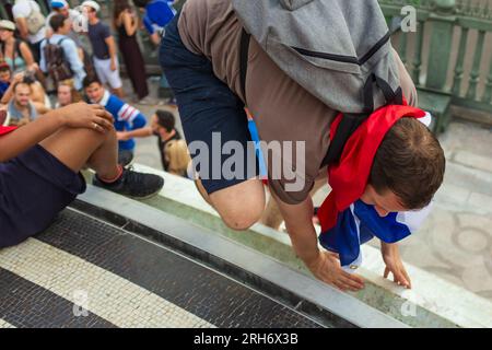 Paris, Frankreich, 2018. Ein sportlicher junger Mann klettert die Juli-Säule hinauf, mit einer französischen Flagge um den Hals, um die französische Fußballweltmeisterschaft zu feiern Stockfoto