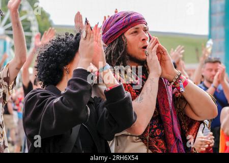 Winchester, Großbritannien. 13. Aug. 2023. Besucher, die Livemusik beim Boomtown Fair Festival genießen. Boomtown alias Boomtown Fair ist ein britisches Musikfestival, das jährlich im South Downs National Park in der Nähe von Winchester, Hampshire, stattfindet. Seit 2009 bietet Boomtown ein vielfältiges Angebot an Bands, DJs und Rednern auf vielen verschiedenen Bühnen an. Jedes jährliche Event wird als „ein Kapitel“ bezeichnet und erweitert die Story des Vorjahres, erzählt durch die Sets und Live-Schauspieler, die durch die Stätte schlendern. Kredit: SOPA Images Limited/Alamy Live News Stockfoto