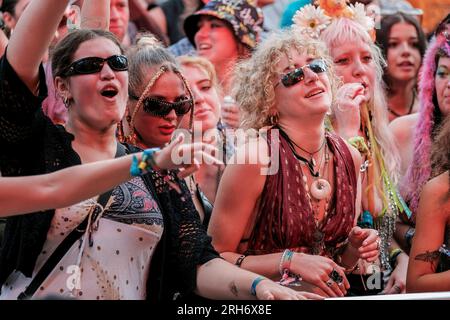 Winchester, Großbritannien. 13. Aug. 2023. Besucher, die Livemusik beim Boomtown Fair Festival genießen. Boomtown alias Boomtown Fair ist ein britisches Musikfestival, das jährlich im South Downs National Park in der Nähe von Winchester, Hampshire, stattfindet. Seit 2009 bietet Boomtown ein vielfältiges Angebot an Bands, DJs und Rednern auf vielen verschiedenen Bühnen an. Jedes jährliche Event wird als „ein Kapitel“ bezeichnet und erweitert die Story des Vorjahres, erzählt durch die Sets und Live-Schauspieler, die durch die Stätte schlendern. Kredit: SOPA Images Limited/Alamy Live News Stockfoto