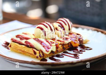 Vollkornmehl belgische Waffel mit einer Schaufel Eis und Beerensauce, Nahaufnahme, Kopierraum. Belgische Waffel mit Eis, Beerensirup und frisch Stockfoto