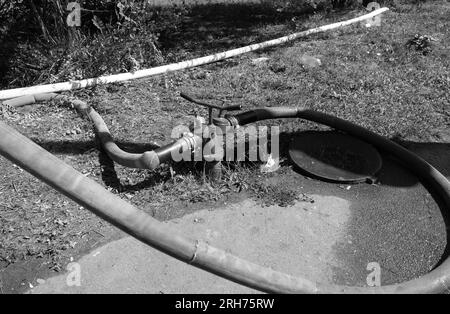 Alte undichte Schläuche eines Löschmotors Pumpen Wasser aus einem Hydranten, während sie einen Brand löschen Stockfoto