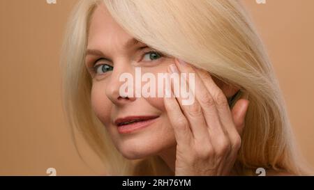 Nahaufnahme reife ältere Frau 50s-Modell mit Pipette Tropfen Serum Vitamin C Öl auf Wange Beauty Gesicht Hautpflege Hyaluronsäure Feuchtigkeitsspendender Stockfoto