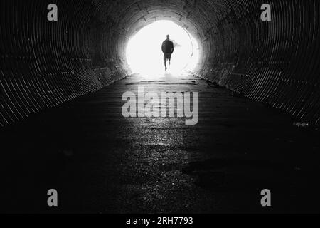 Licht am Ende des Tunnels mit der Silhouette des Menschen. In Schwarzweiß. Stockfoto