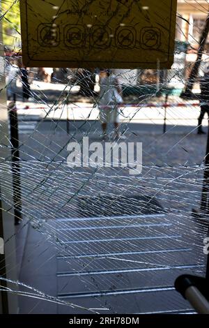 Zerbrochenes Glas an der Eingangstür des Supermarkts. Moderne, modische gepanzerte Glastür in einem Netz aus Rissen nach einem Akt des Vandalismus während des Krieges. Stockfoto