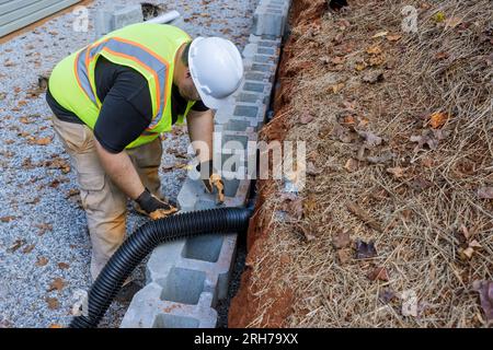 Das Bauteam arbeitet derzeit daran, Abflussrohre für Regenwasser in der Haltewand zu verlegen. Stockfoto