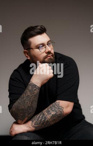 Bärtiger und tätowierter Mann in Schwarz Stockfoto