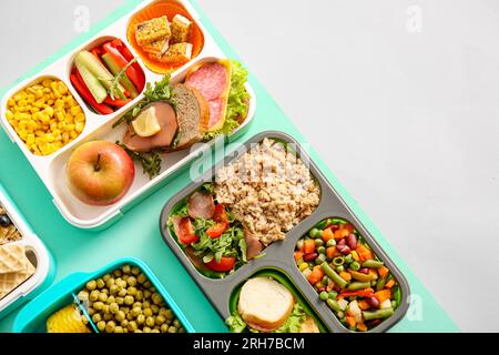 Lunchboxen mit verschiedenen köstlichen Speisen auf farbigem Hintergrund Stockfoto