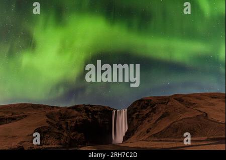 Der Wasserfall von Skógafoss im Süden Islands von 60m, der bei Nacht im Mondschein unter den Nordlichtern (Aurora Borealis) zu sehen ist Stockfoto