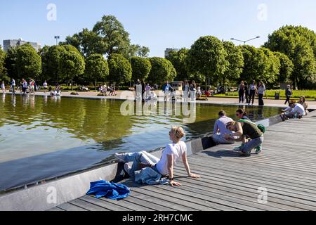 Moskau, Russland - 2023. Mai, Gorky Central Park of Culture and Leisure. Die Leute ruhen sich auf dem Pier in der Nähe des künstlichen Teiches nahe Fontain aus. Ein glücklicher Coup Stockfoto
