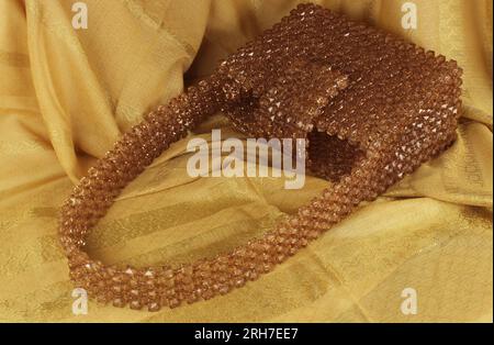 Handgefertigte Nerzperlen-Tasche auf gelbem Stoff. Stockfoto