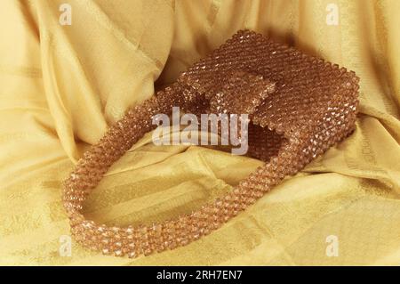 Handgefertigte Nerzperlen-Tasche auf gelbem Stoff. Stockfoto