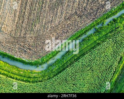 Aerial view of cultivated agricultural farmland divided by a stream with water for watering Stockfoto