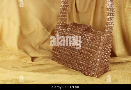 Handgefertigte Nerzperlen-Tasche auf gelbem Stoff. Stockfoto